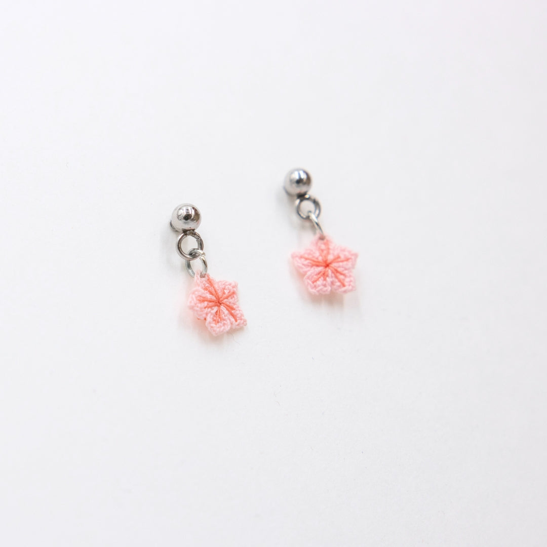 Pair of earrings with pink floral charms on a white background