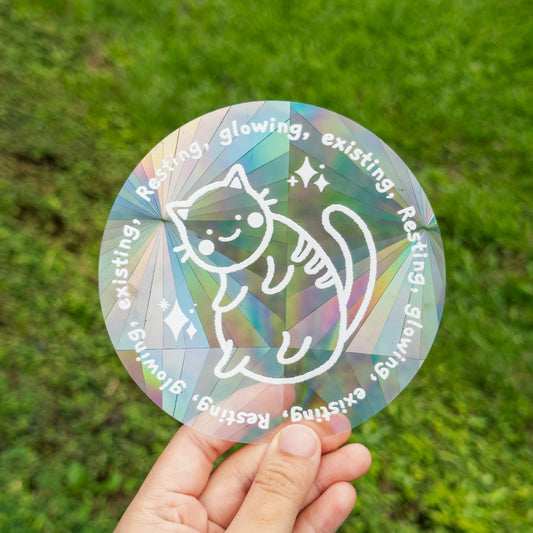 Holographic sticker with cat design held in front of grass