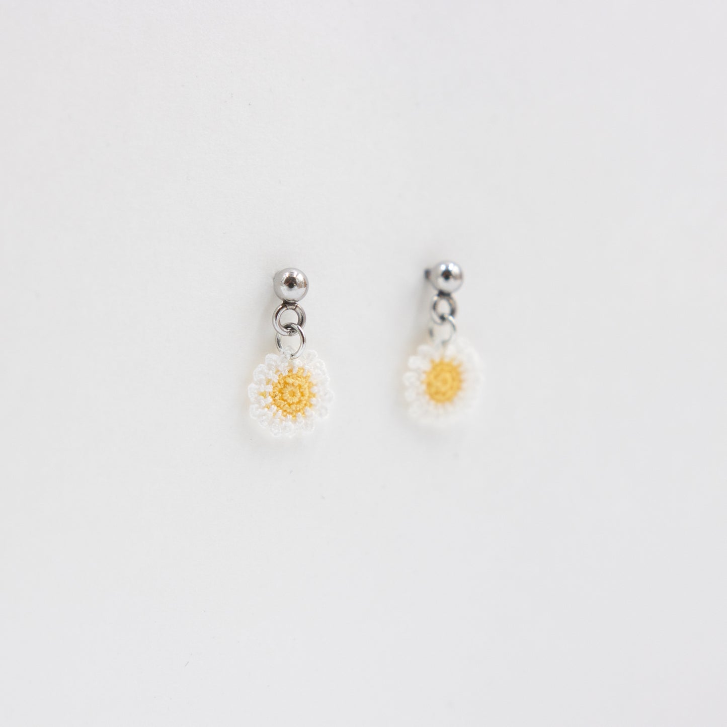 Pair of daisy-shaped earrings on a light gray background