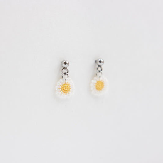Pair of daisy-shaped earrings on a light gray background