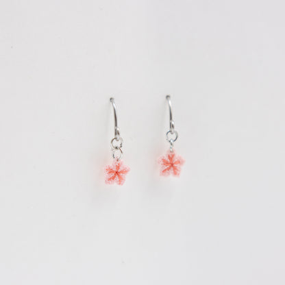 Pair of silver earrings with pink flower charms on a light gray background