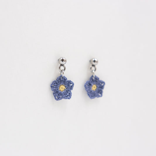 Pair of blue flower-shaped earrings on a light gray background